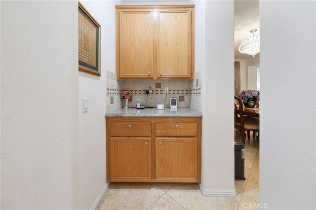 12830 Wildflower Ln, Riverside, CA 92503 - bar area featuring decorative backsplash, light tile patterned floors, baseboards, and a chandelier