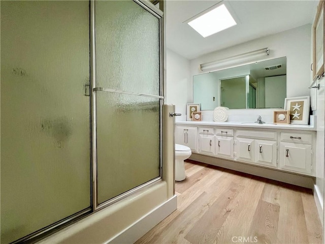 13580 Medinac Ln Unit M5-E, Seal Beach, CA 90740 - bathroom with wood finished floors, toilet, vanity, and bath / shower combo with glass door