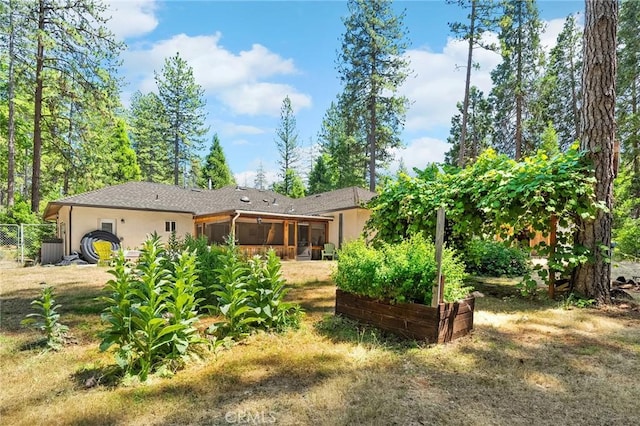 4930 Contentment Ln, Forest Ranch, CA 95942 - rear view of house with a sunroom, stucco siding, and a vegetable garden
