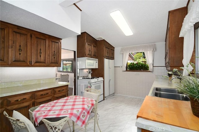 3935 Oakfield Dr, Sherman Oaks, CA 91423 - kitchen featuring white appliances, a sink, light countertops, lofted ceiling, and tile walls