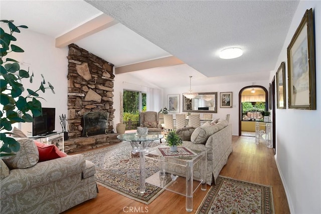 3935 Oakfield Dr, Sherman Oaks, CA 91423 - living room with wood finished floors, beamed ceiling, a fireplace, a textured ceiling, and baseboards