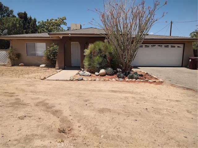 7870 Hopi Trl, Yucca Valley, CA 92284 - view of front of home featuring stucco siding, driveway, and an attached garage