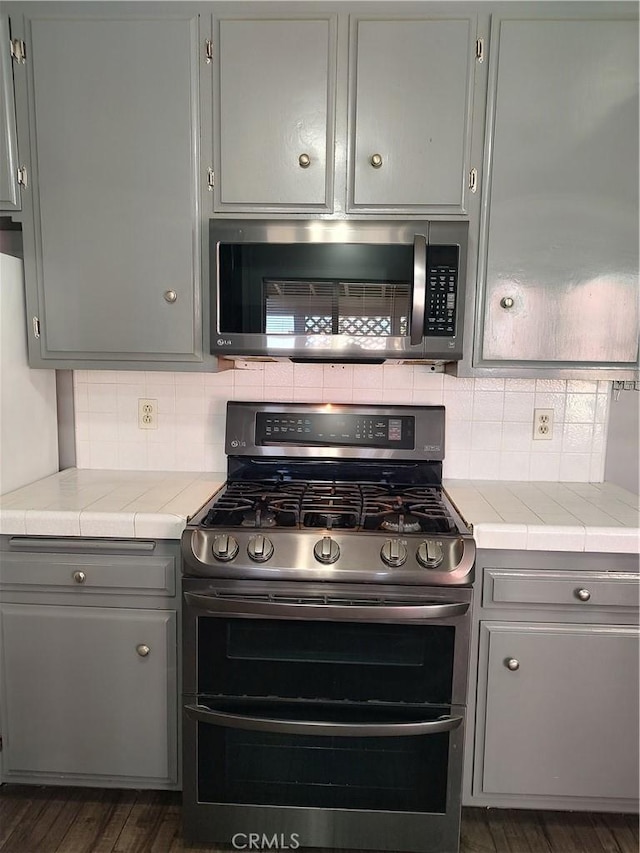 7870 Hopi Trl, Yucca Valley, CA 92284 - kitchen featuring appliances with stainless steel finishes, gray cabinetry, dark wood finished floors, and decorative backsplash