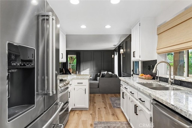 13 Noyo Ct, Chico, CA 95973 - kitchen featuring appliances with stainless steel finishes, a sink, white cabinetry, light wood-type flooring, and light stone counters