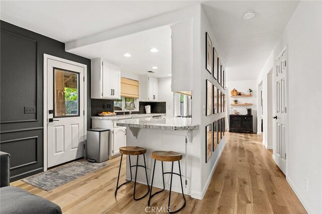 13 Noyo Ct, Chico, CA 95973 - kitchen with white cabinets, light wood-type flooring, a breakfast bar area, a peninsula, and a sink