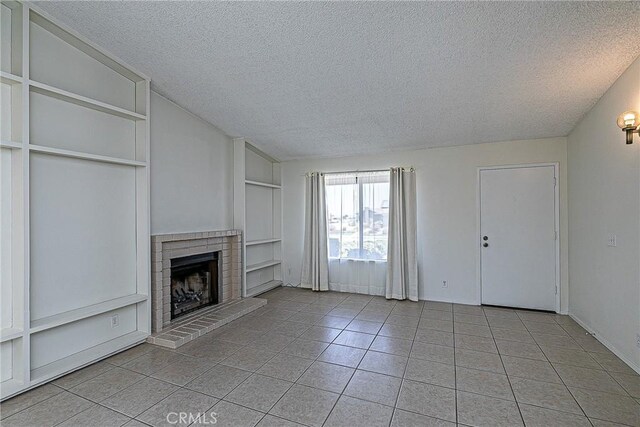 1168 E Foster Rd Unit B, Santa Maria, CA 93455 - unfurnished living room with a textured ceiling, a fireplace, built in shelves, and light tile patterned floors