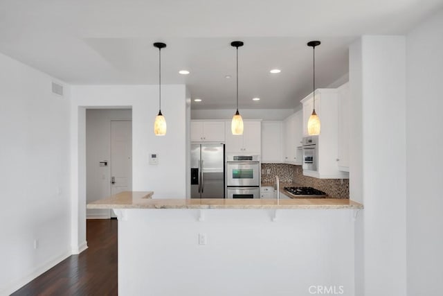 1539 Windshore Way, Oxnard, CA 93035 - kitchen with appliances with stainless steel finishes, a peninsula, dark wood-type flooring, white cabinets, and a kitchen bar