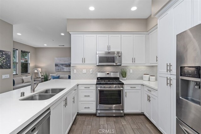 78 Patria, Rancho Mission Viejo, CA 92694 - kitchen featuring appliances with stainless steel finishes, white cabinetry, light countertops, dark wood finished floors, and backsplash