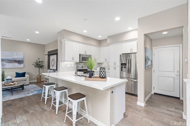 78 Patria, Rancho Mission Viejo, CA 92694 - kitchen with stainless steel fridge with ice dispenser, a peninsula, a kitchen breakfast bar, light wood-type flooring, and white cabinetry
