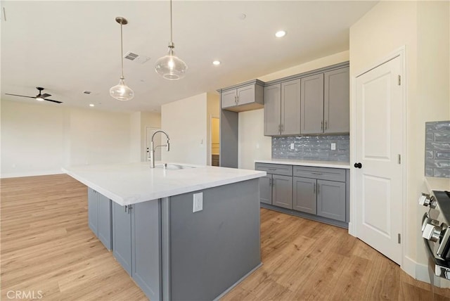 2395 Tokay Ct, Paradise, CA 95969 - kitchen with gray cabinets, a sink, light wood-type flooring, tasteful backsplash, and recessed lighting