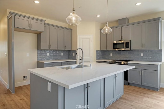 2395 Tokay Ct, Paradise, CA 95969 - kitchen featuring a sink, stainless steel appliances, gray cabinetry, light wood-style floors, and a kitchen island with sink