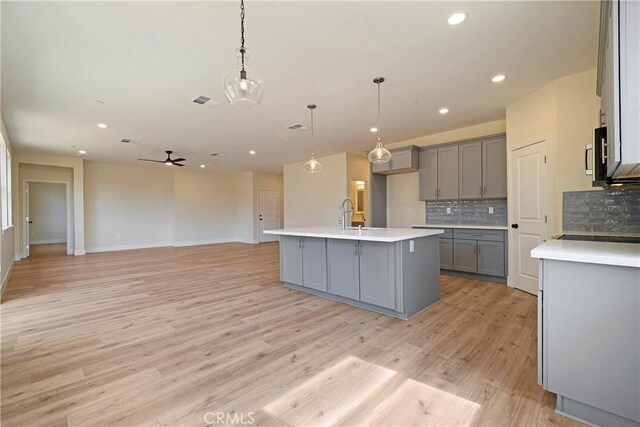 2395 Tokay Ct, Paradise, CA 95969 - kitchen featuring gray cabinets, tasteful backsplash, light wood finished floors, light countertops, and a ceiling fan
