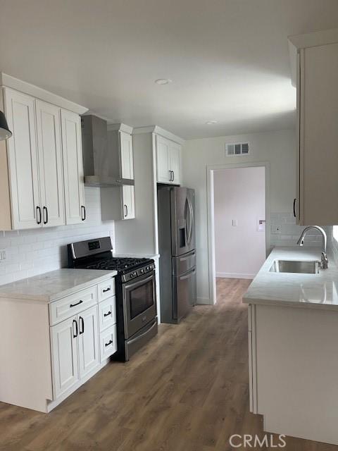 21329 Jaffrey Ave, Torrance, CA 90502 - kitchen featuring appliances with stainless steel finishes, a sink, wall chimney range hood, decorative backsplash, and white cabinets