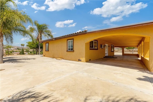 5071 Bushnell Ave, Riverside, CA 92505 - view of side of home with stucco siding, driveway, crawl space, and an AC wall unit