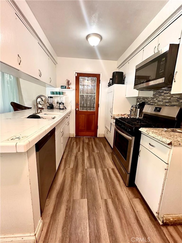 3346 Sunnyside Dr, Riverside, CA 92506 - kitchen featuring appliances with stainless steel finishes, a sink, light wood-type flooring, and white cabinetry