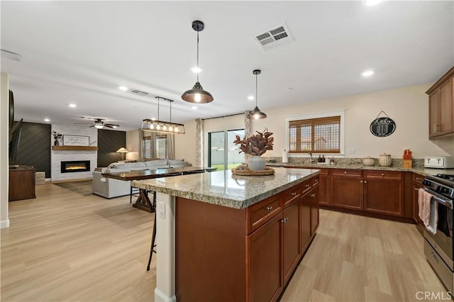 29377 Wyatt Earp Way, Winchester, CA 92596 - kitchen featuring a large fireplace, light wood finished floors, gas range oven, a center island, and pendant lighting