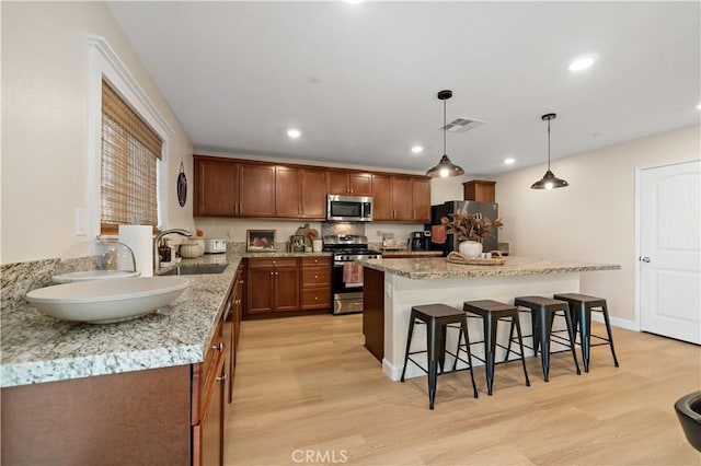 29377 Wyatt Earp Way, Winchester, CA 92596 - kitchen featuring stainless steel appliances, a sink, a kitchen bar, light wood finished floors, and recessed lighting