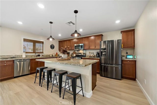 29377 Wyatt Earp Way, Winchester, CA 92596 - kitchen with stainless steel appliances, a kitchen bar, light wood-type flooring, a kitchen island, and recessed lighting