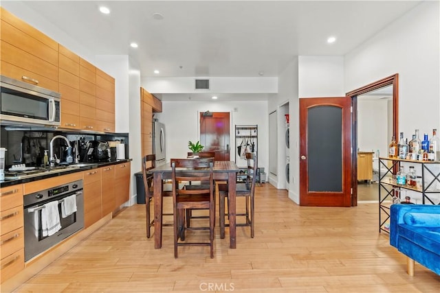 460 S Spring St Unit 613, Los Angeles, CA 90013 - kitchen with appliances with stainless steel finishes, light wood finished floors, dark countertops, recessed lighting, and modern cabinets