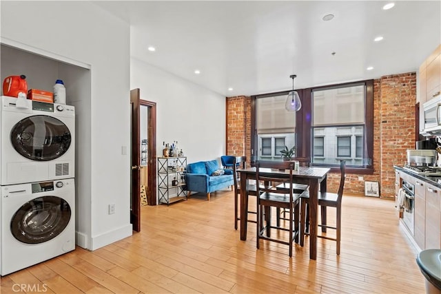 460 S Spring St Unit 613, Los Angeles, CA 90013 - kitchen featuring stacked washer and clothes dryer, light wood finished floors, recessed lighting, white microwave, and hanging light fixtures
