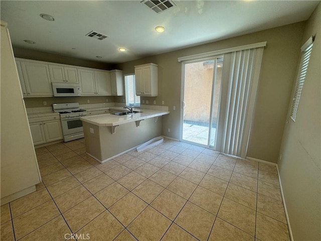 9757 Edenbrook Dr, Riverside, CA 92503 - kitchen featuring white appliances, light tile patterned floors, a peninsula, white cabinetry, and a sink