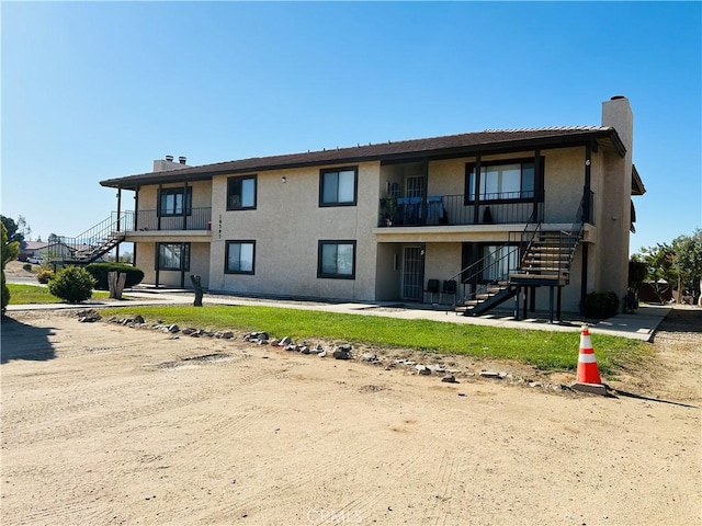 16585 Green Tree Blvd, Victorville, CA 92395 - back of house featuring stairway, a chimney, stucco siding, and a balcony