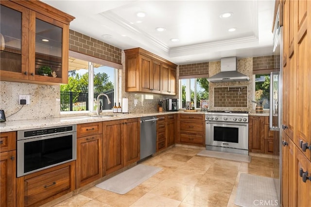 6021 Saddletree Ln, Yorba Linda, CA 92886 - kitchen featuring wall chimney exhaust hood, appliances with stainless steel finishes, decorative backsplash, a raised ceiling, and brown cabinets