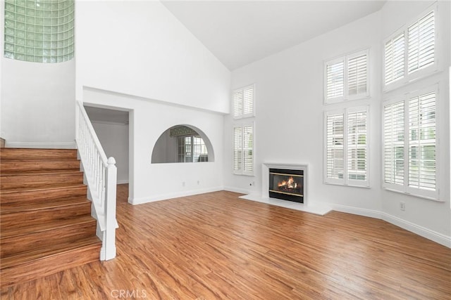 24545 Santa Clara Ave, Dana Point, CA 92629 - unfurnished living room with high vaulted ceiling, a fireplace with flush hearth, light wood-type flooring, and stairs