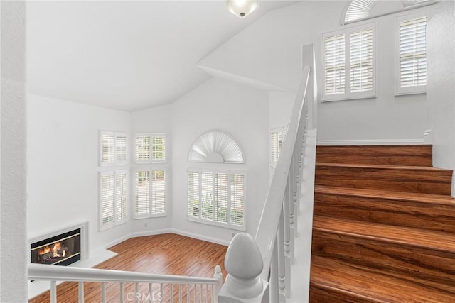 24545 Santa Clara Ave, Dana Point, CA 92629 - staircase featuring wood finished floors, a glass covered fireplace, and vaulted ceiling