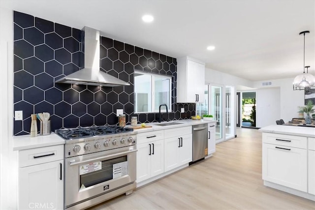 12009 Dresden Pl, Granada Hills, CA 91344 - kitchen featuring wall chimney range hood, appliances with stainless steel finishes, a sink, backsplash, and light wood-type flooring