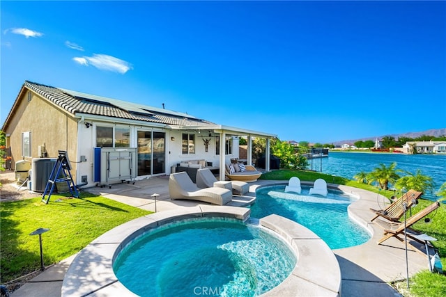 84290 Tramonto Way, Indio, CA 92203 - back of house featuring roof mounted solar panels, an outdoor hangout area, a patio, a pool with connected hot tub, and stucco siding