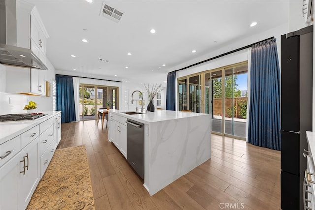 112 Sentosa, Irvine, CA 92618 - kitchen featuring wall chimney exhaust hood, appliances with stainless steel finishes, a sink, light wood-type flooring, and an island with sink