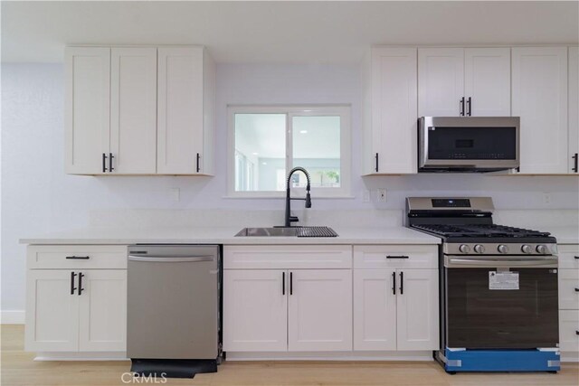 25411 Cottage Ave, Loma Linda, CA 92354 - kitchen with stainless steel appliances, white cabinets, light countertops, and light wood-type flooring