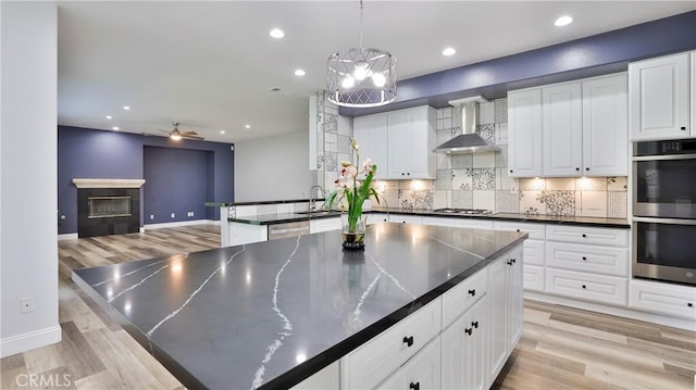 2431 Elizabeth Ct, Upland, CA 91784 - kitchen with wall chimney exhaust hood, stainless steel appliances, dark countertops, decorative backsplash, and a ceiling fan