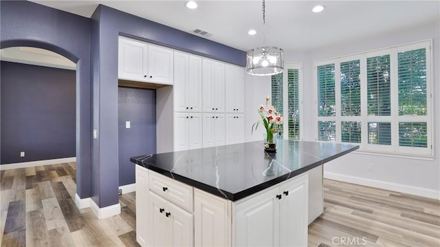 2431 Elizabeth Ct, Upland, CA 91784 - kitchen with arched walkways, light wood-style flooring, dark countertops, white cabinets, and recessed lighting