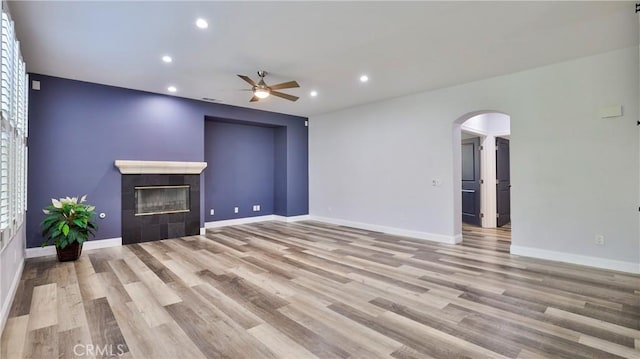 2431 Elizabeth Ct, Upland, CA 91784 - unfurnished living room with ceiling fan, a tiled fireplace, arched walkways, wood finished floors, and recessed lighting