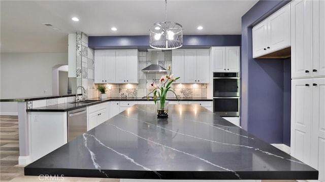 2431 Elizabeth Ct, Upland, CA 91784 - kitchen with stainless steel appliances, wall chimney range hood, backsplash, recessed lighting, and arched walkways