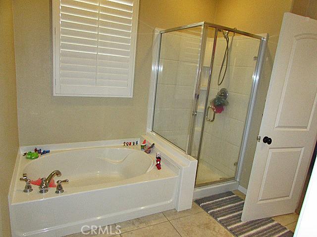 3981 E Emory Ln Unit 6, Ontario, CA 91761 - bathroom featuring tile patterned flooring, a bath, and a stall shower
