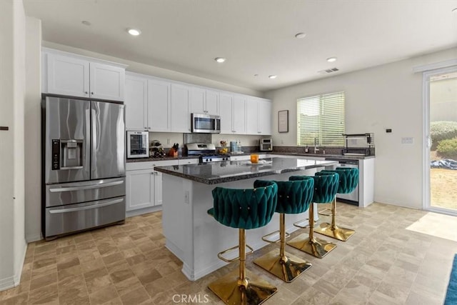 1023 Barberry Ln, Calimesa, CA 92320 - kitchen with stainless steel appliances, a center island, white cabinets, a breakfast bar area, and recessed lighting