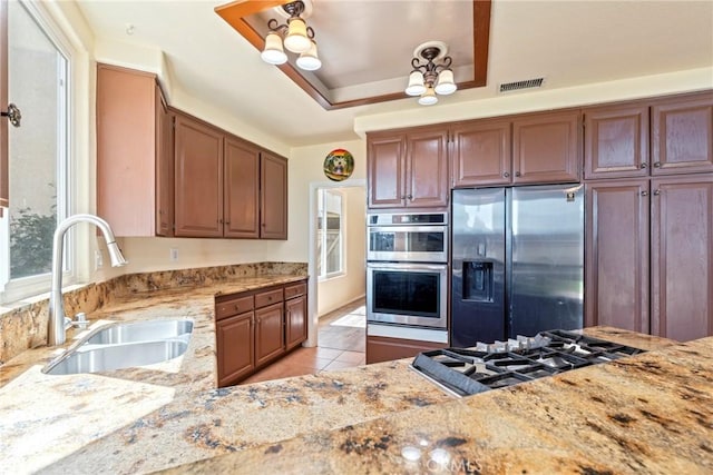 24101 Crowned Partridge Ln, Murrieta, CA 92562 - kitchen featuring stainless steel appliances, light stone counters, light tile patterned floors, and brown cabinetry