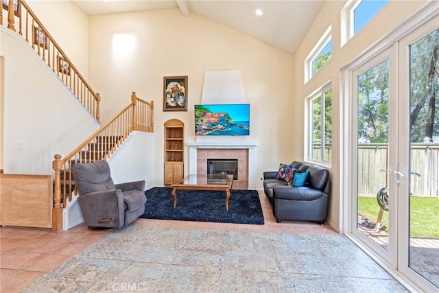 24101 Crowned Partridge Ln, Murrieta, CA 92562 - tiled living area featuring high vaulted ceiling, stairs, a tile fireplace, beamed ceiling, and french doors
