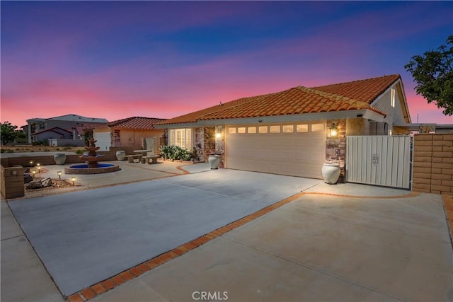 27470 Lakeview Dr, Helendale, CA 92342 - mediterranean / spanish-style house featuring an attached garage, driveway, a tile roof, stone siding, and stucco siding