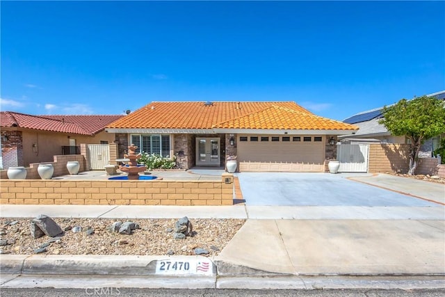 27470 Lakeview Dr, Helendale, CA 92342 - view of front facade featuring an attached garage, a tile roof, concrete driveway, french doors, and a gate