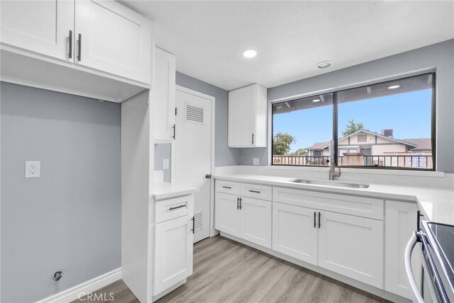 12830 Perris Blvd Unit C10, Moreno Valley, CA 92553 - kitchen with a sink, white cabinets, light wood-style flooring, light countertops, and recessed lighting