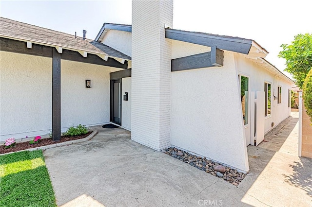 11591 Palawan St, Cypress, CA 90630 - entrance to property featuring stucco siding, a patio area, a chimney, and a shingled roof