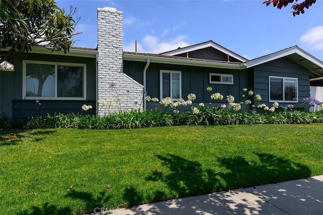 17132 Emerald Ln, Huntington Beach, CA 92647 - view of property exterior with a chimney, a lawn, and board and batten siding