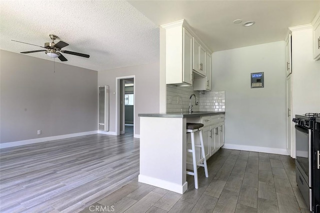 17132 Emerald Ln, Huntington Beach, CA 92647 - kitchen featuring gas stove, ceiling fan, dark wood-style flooring, dark countertops, and baseboards