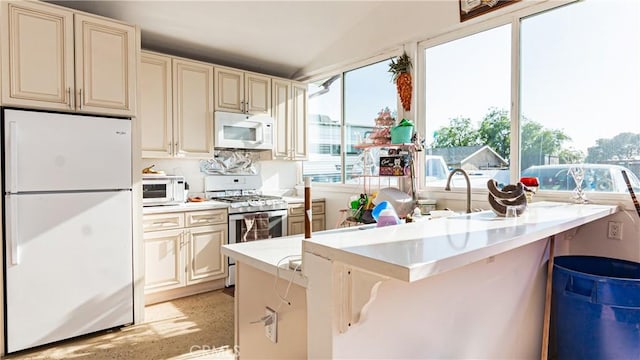 9828 Carob Ave, Fontana, CA 92335 - kitchen featuring white appliances, cream cabinets, a peninsula, lofted ceiling, and light countertops