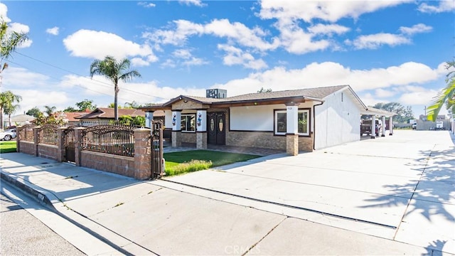 9828 Carob Ave, Fontana, CA 92335 - view of front of house with stone siding, a fenced front yard, a gate, and stucco siding