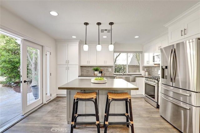 55 Fairfield, Lake Forest, CA 92610 - kitchen featuring stainless steel appliances, backsplash, white cabinets, a center island, and recessed lighting